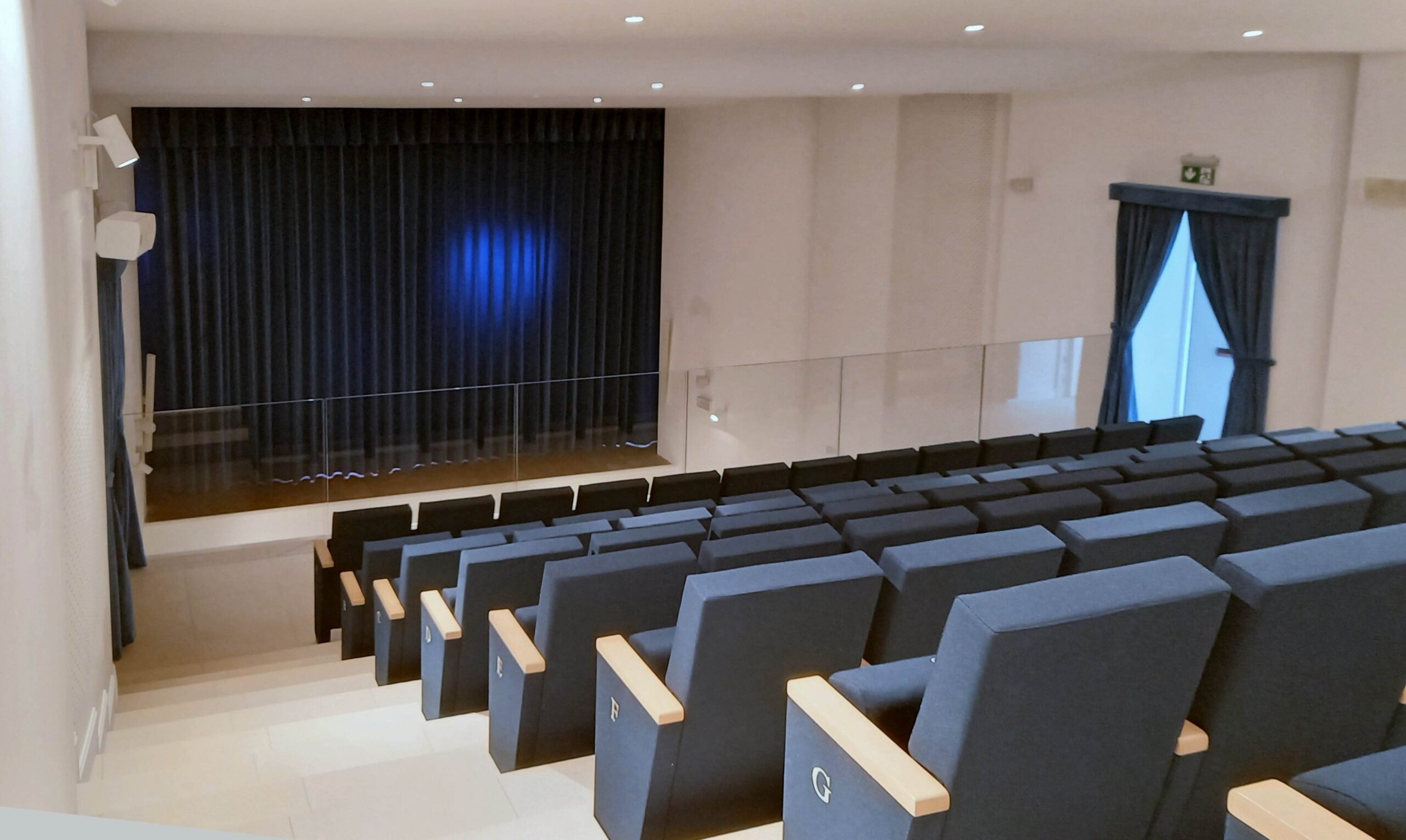 Vista laterale della platea del teatro di Calcinato con poltrone numerate, sipario e diffusori a parete