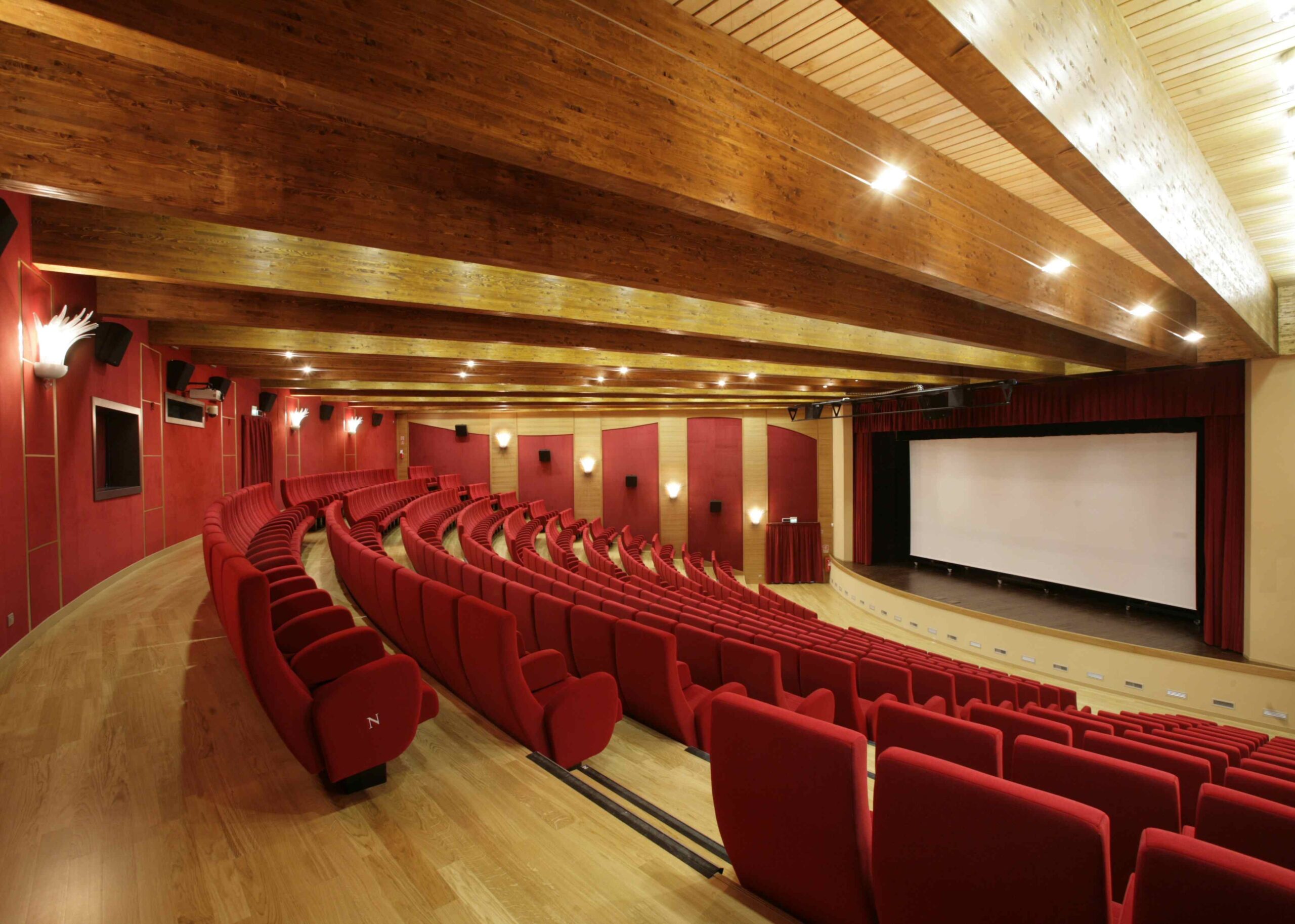 Sala del Teatro Comunale di Mirano con poltrone rosse, soffitto in legno a vista e schermo cinema