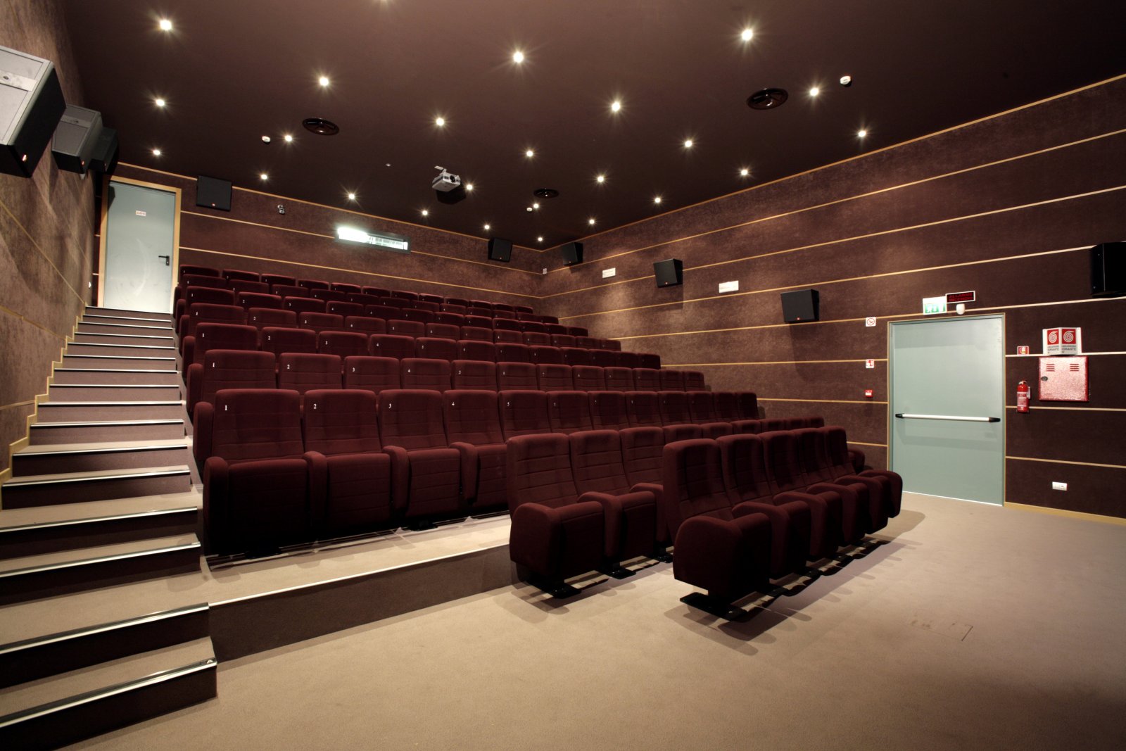 Sala minore del Teatro Comunale di Mirano con poltrone bordeaux, trattamento acustico a parete e gradinata