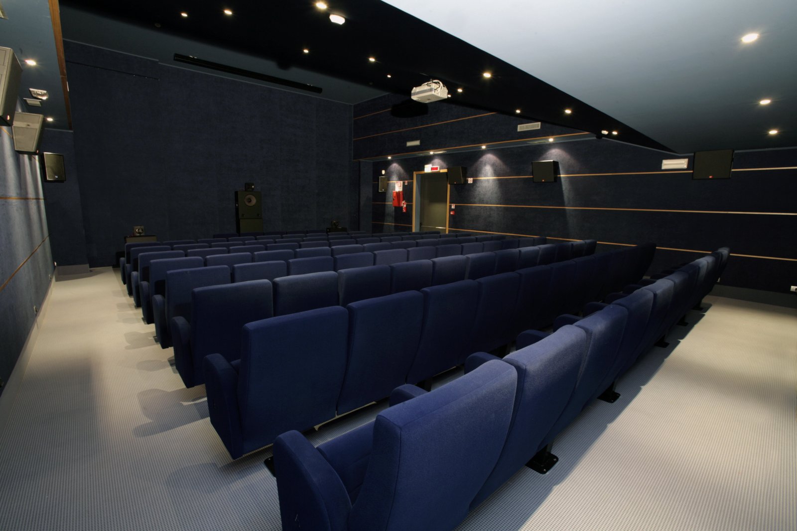 Sala del Teatro Comunale di Mirano con poltrone blu, proiettore e pannelli acustici decorativi a parete