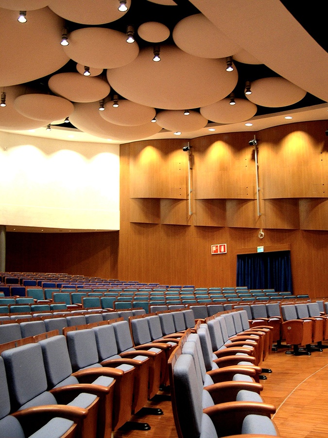 Platea del Teatro Cristallo di Bolzano con poltrone azzurre e pannelli acustici circolari a soffitto