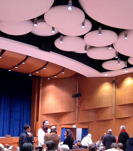 Pubblico nella sala del Teatro Cristallo di Bolzano con pannelli acustici circolari illuminati a soffitto