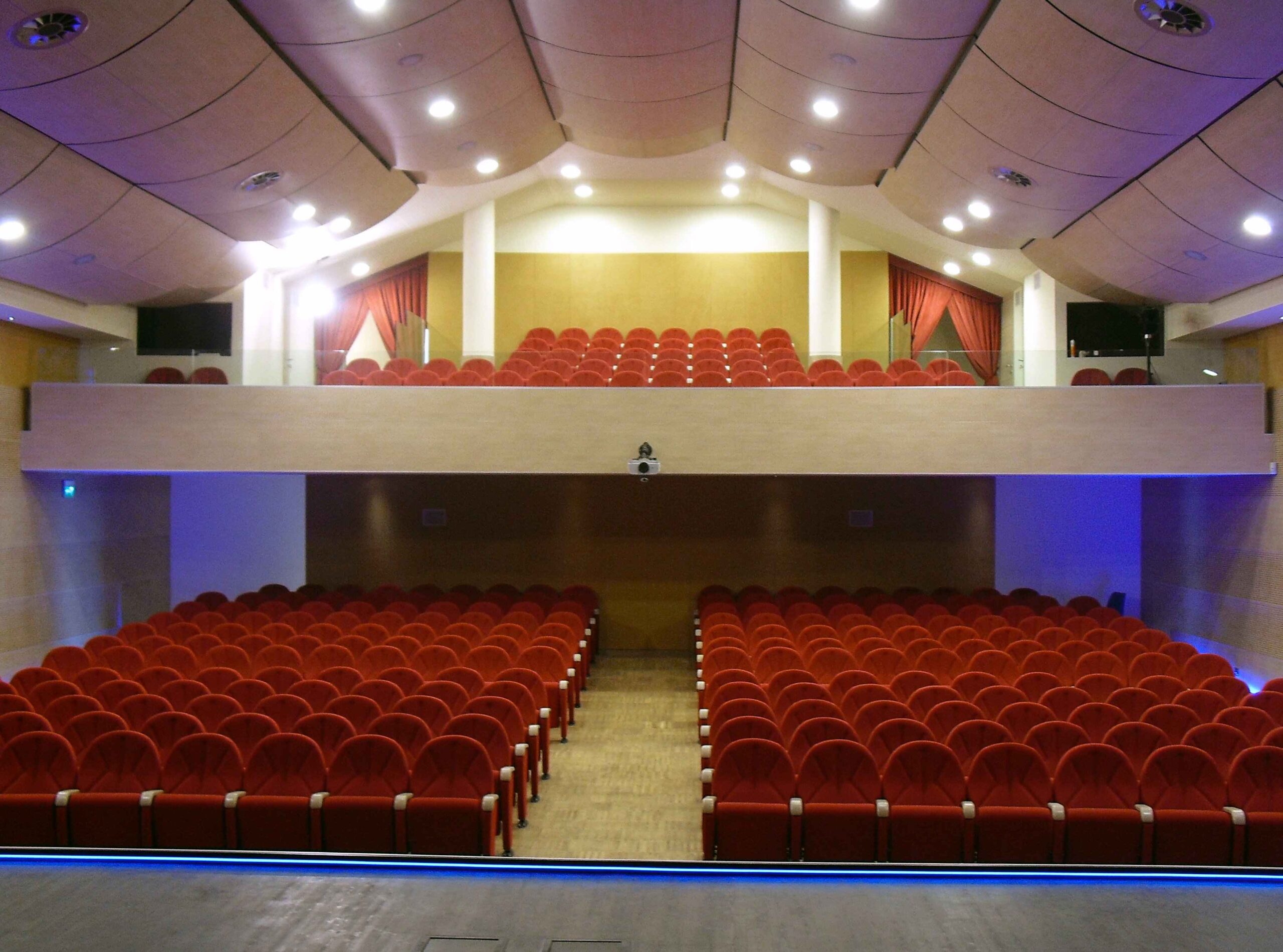 Platea del teatro di Igea Marina con poltrone rosse, balconata e pannelli acustici a soffitto