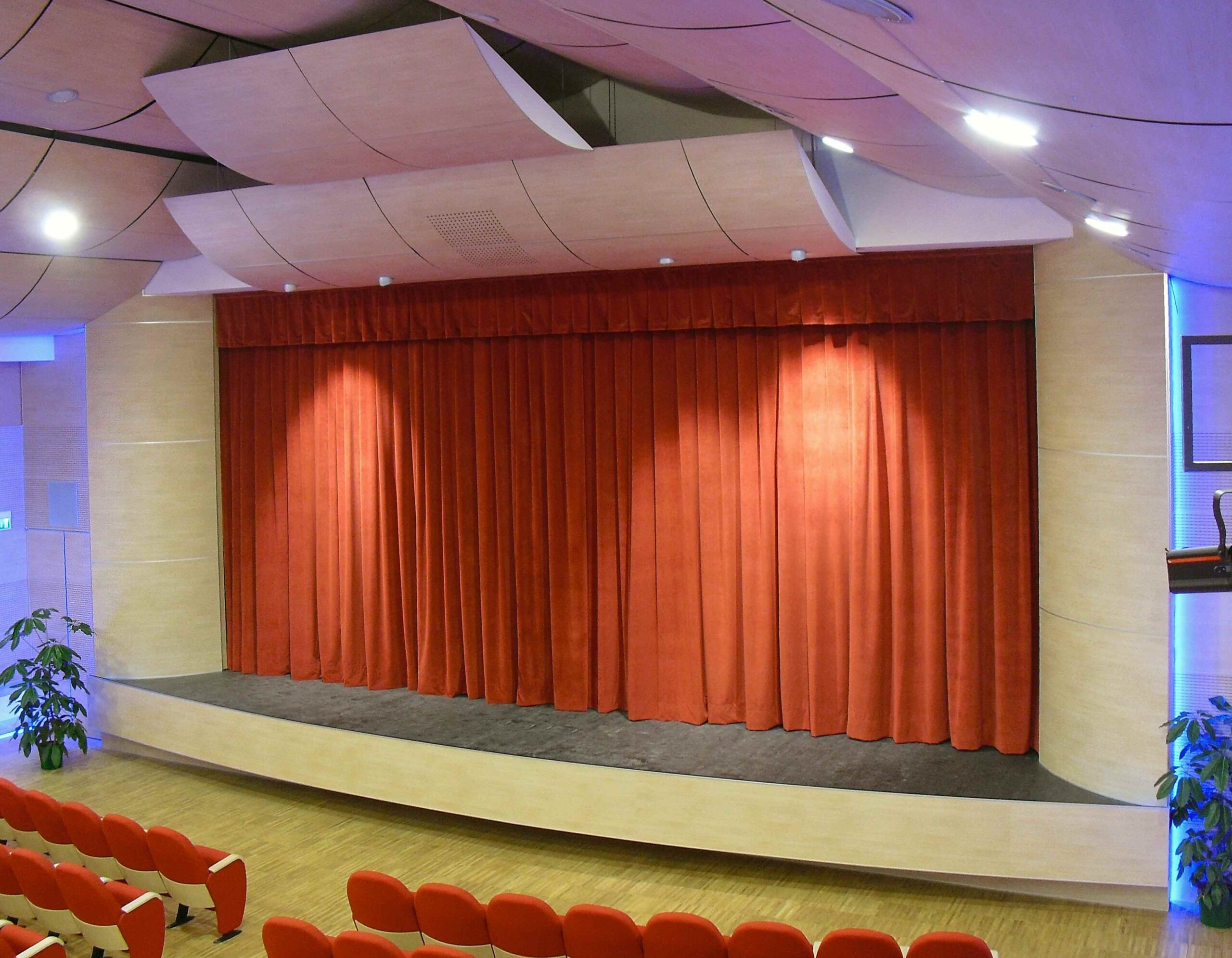 Palcoscenico del teatro di Igea Marina con sipario rosso chiuso e pannelli acustici sagomati a soffitto
