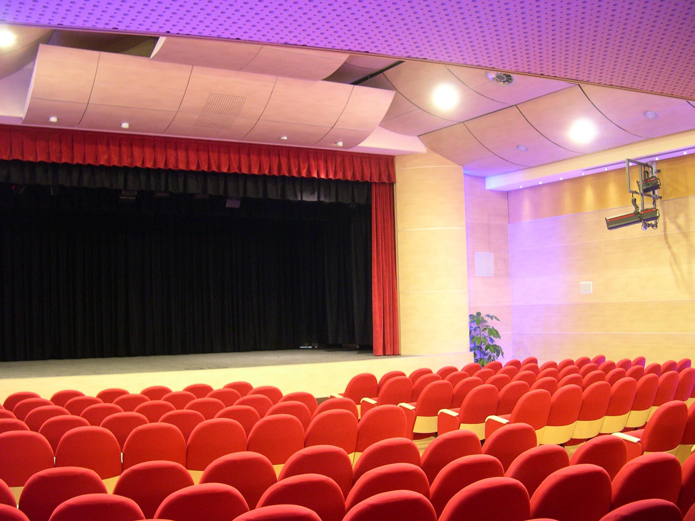 Sala del Teatro di Igea Marina con poltrone rosse, palcoscenico con sipario e pannelli acustici a soffitto