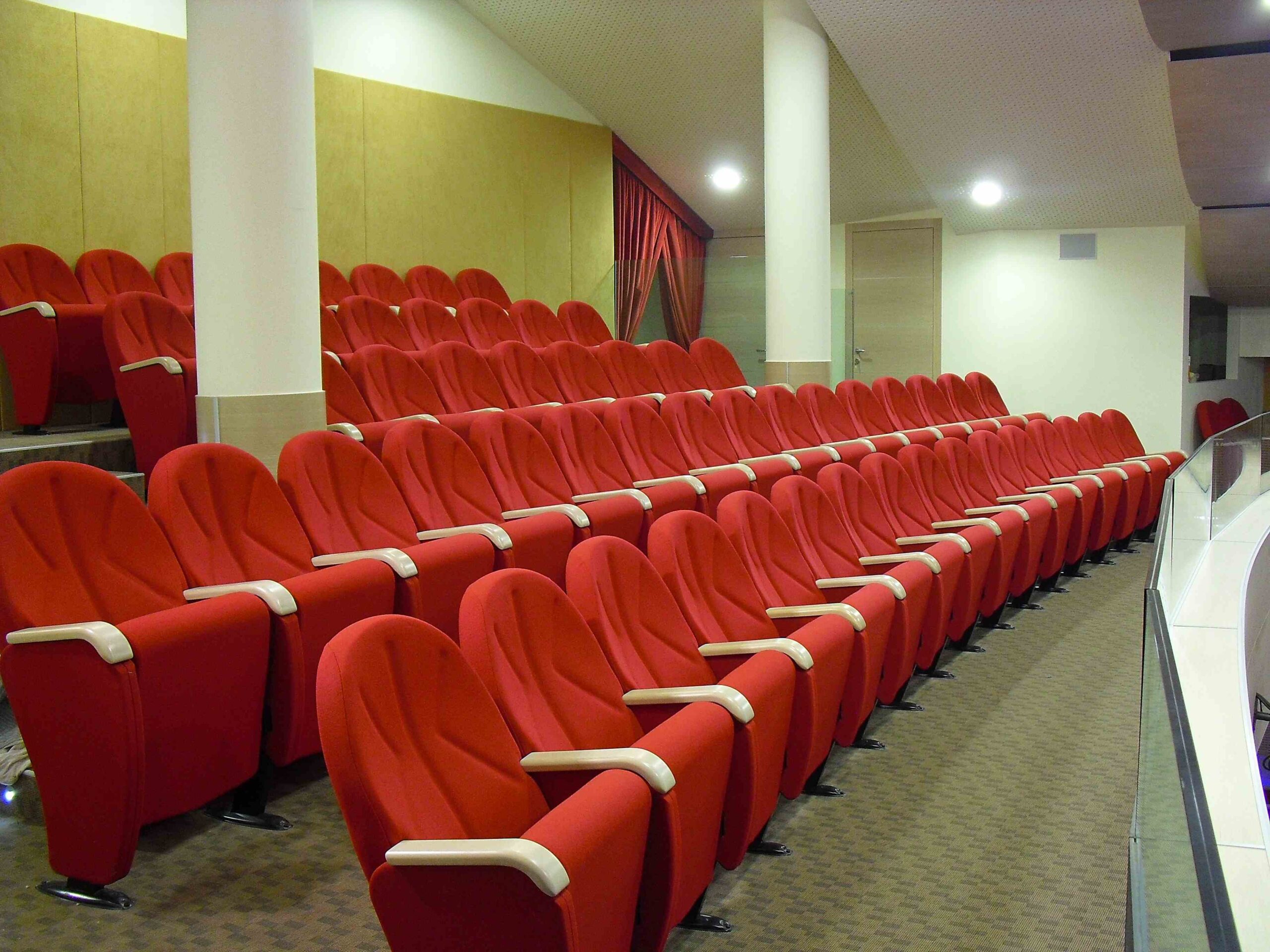 Poltrone rosse imbottite nella galleria superiore del Teatro di Igea Marina con pannelli acustici a parete