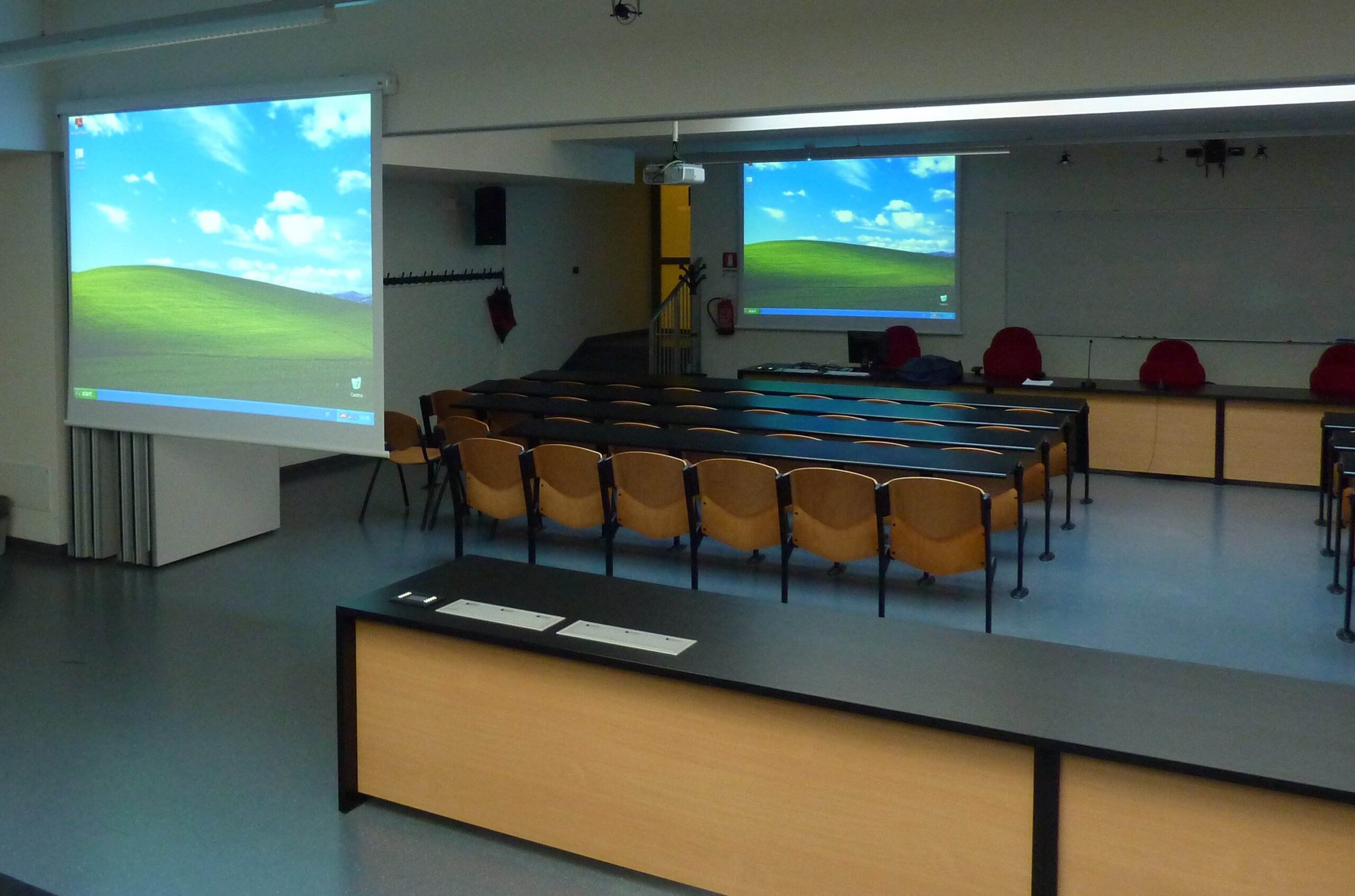 Aula dell'Universita di Trento con doppio schermo di proiezione, cattedra e sedute per studenti