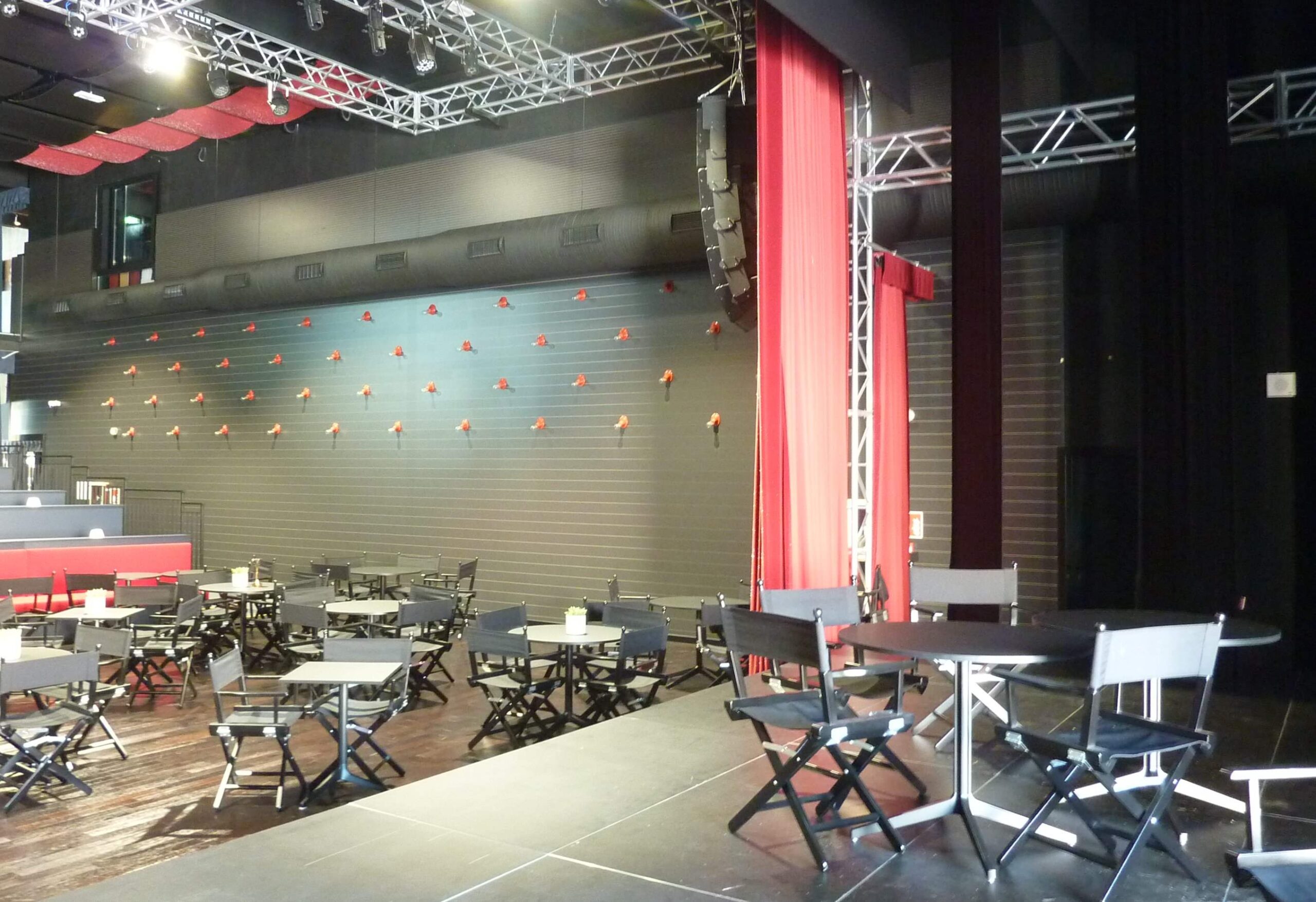 Area palco dello Zomby Club di Inveruno con sipario rosso, tralicci luci, tavoli e sedie pieghevoli